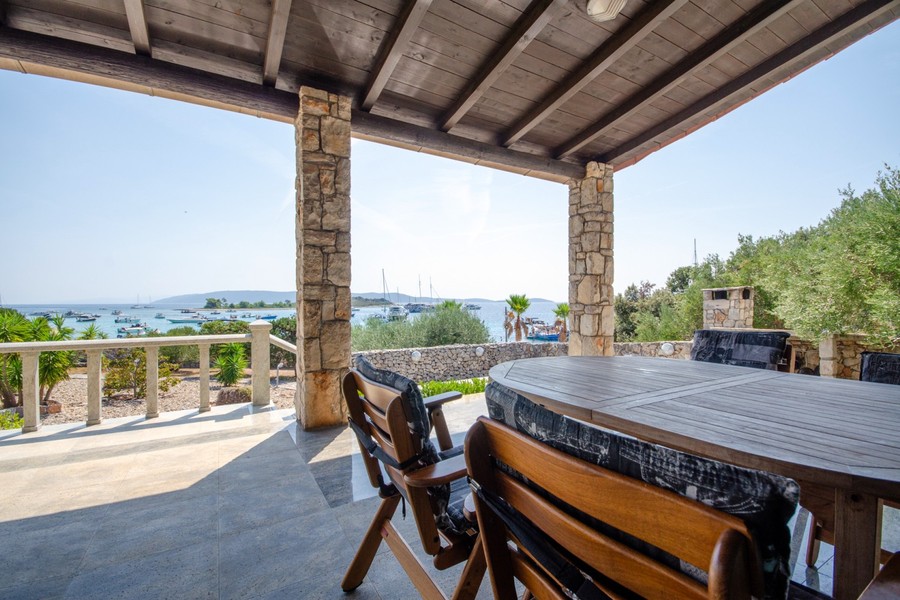 Überdachte Terrasse mit Esstisch und Meerblick
