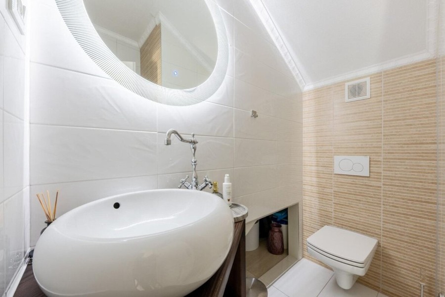 Badezimmer mit Aufsatzwaschbecken und rundem Spiegel