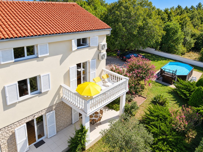Balkon mit Liegestühlen über dem Garten mit Pool