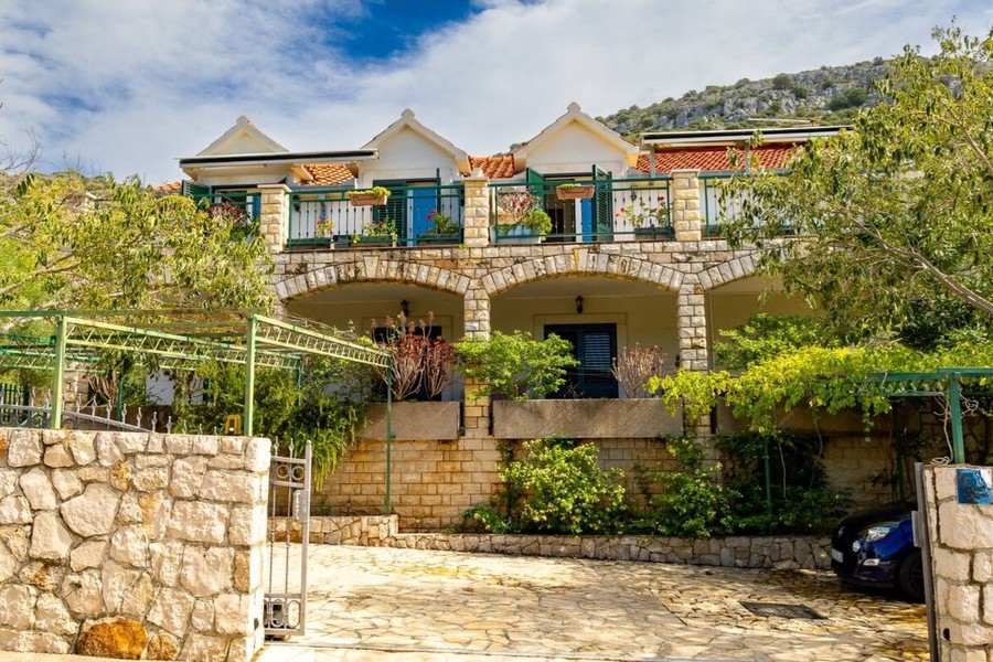 Haus mit Steinmauer und Zufahrt im Grünen