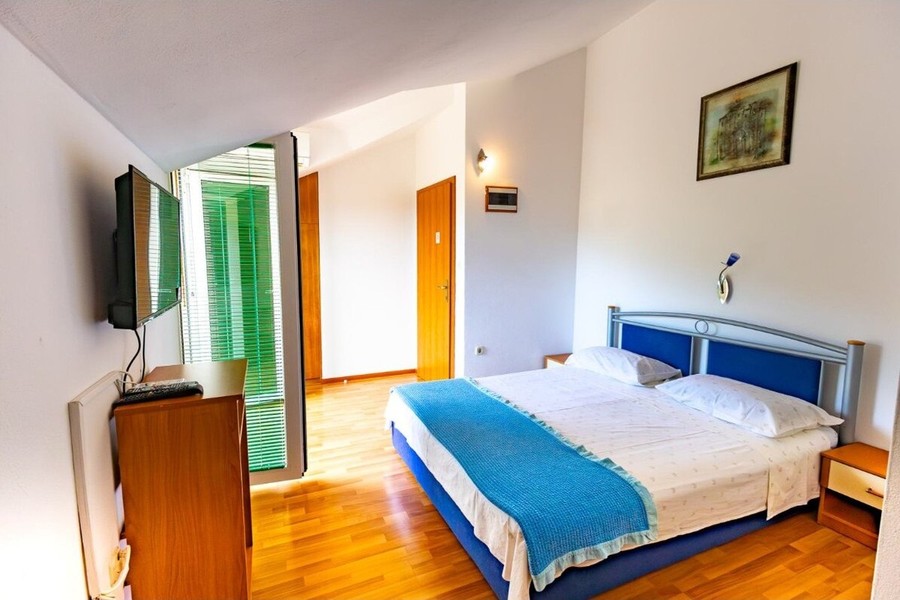 Schlafzimmer mit Doppelbett und Fernseher