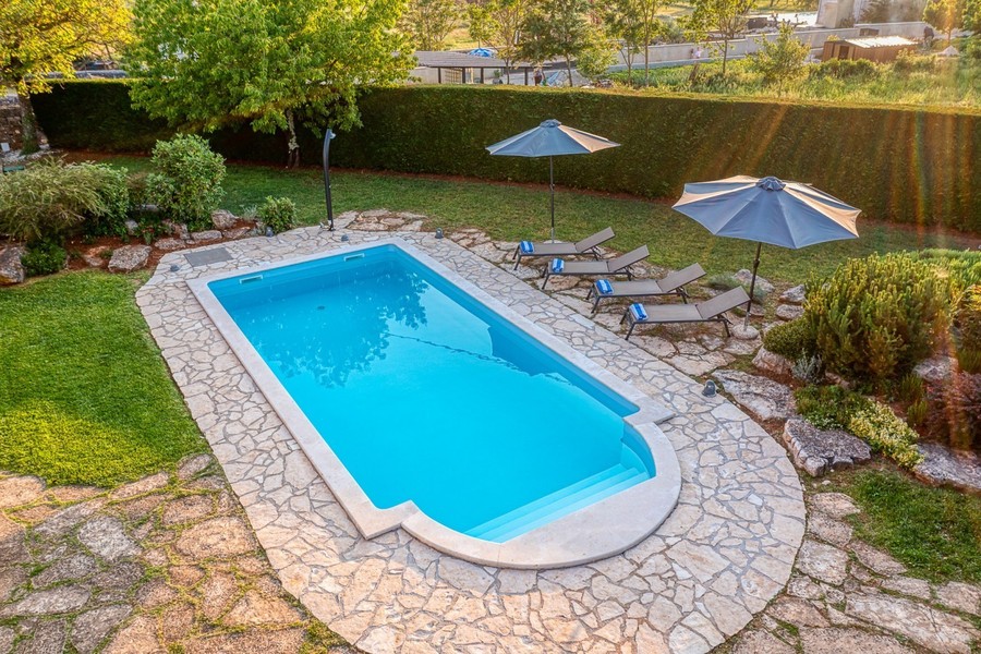 Pool mit Steinumrandung, Liegen und Sonnenschirmen von oben