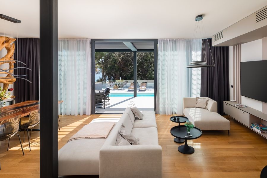 Wohnzimmer mit Sofa und Glasfront zum Pool