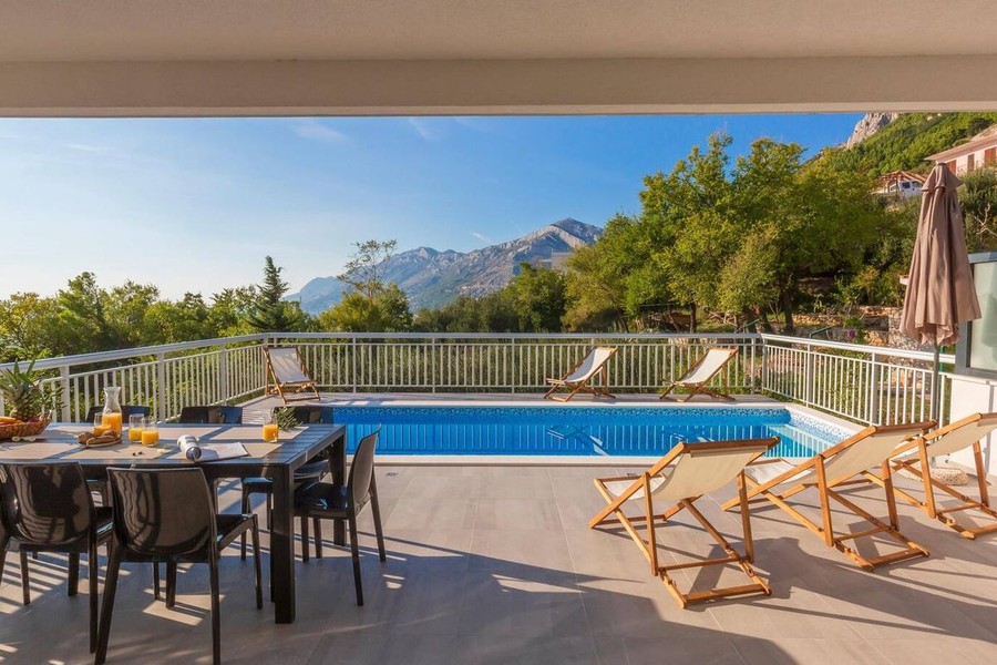 Pool mit Sonnenliegen und Blick auf das Gebirge