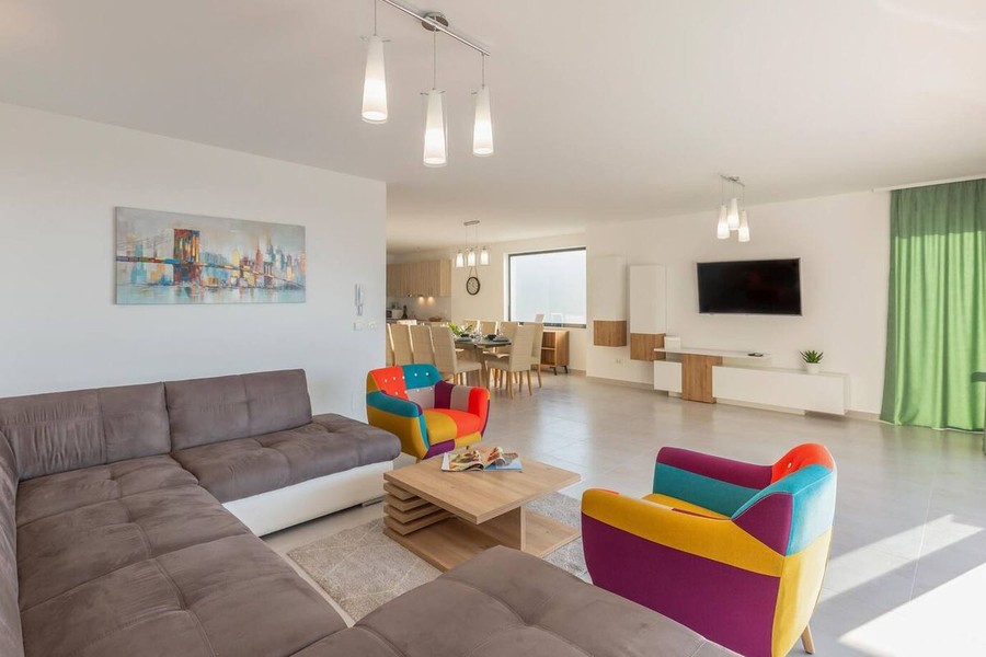 Wohnzimmer mit Ecksofa und bunten Sesseln