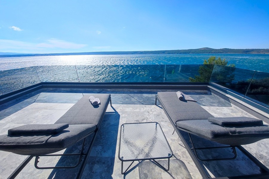 Terrasse mit Sonnenliegen über dem Meer