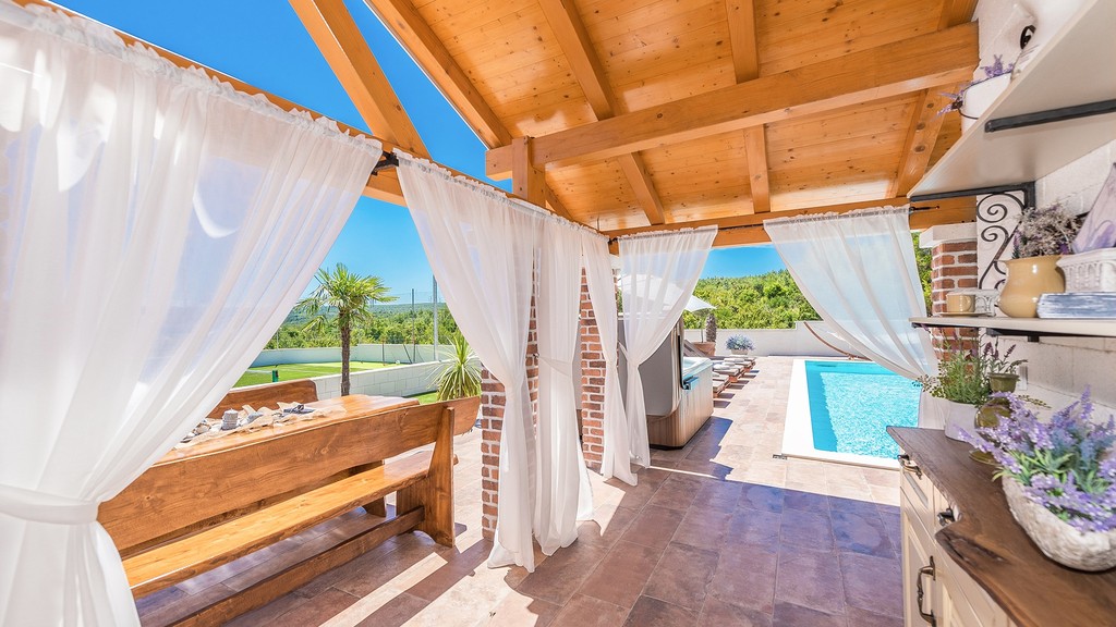 Terrasse mit Holzdach und Blick zum Pool