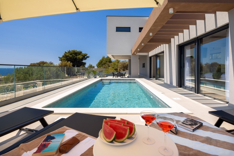 Pool mit Sonnenliegen und Blick auf das Meer