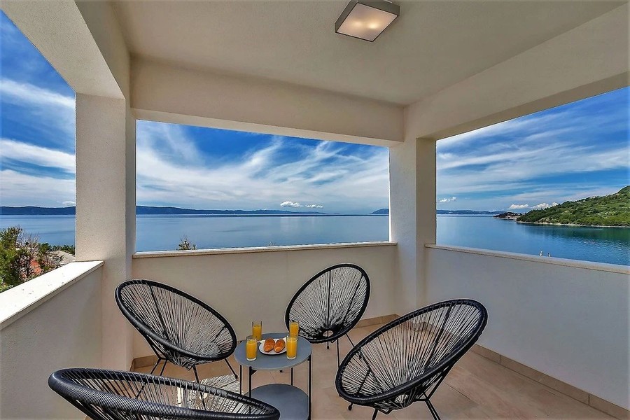 Überdachte Terrasse mit Sesseln und Meerblick