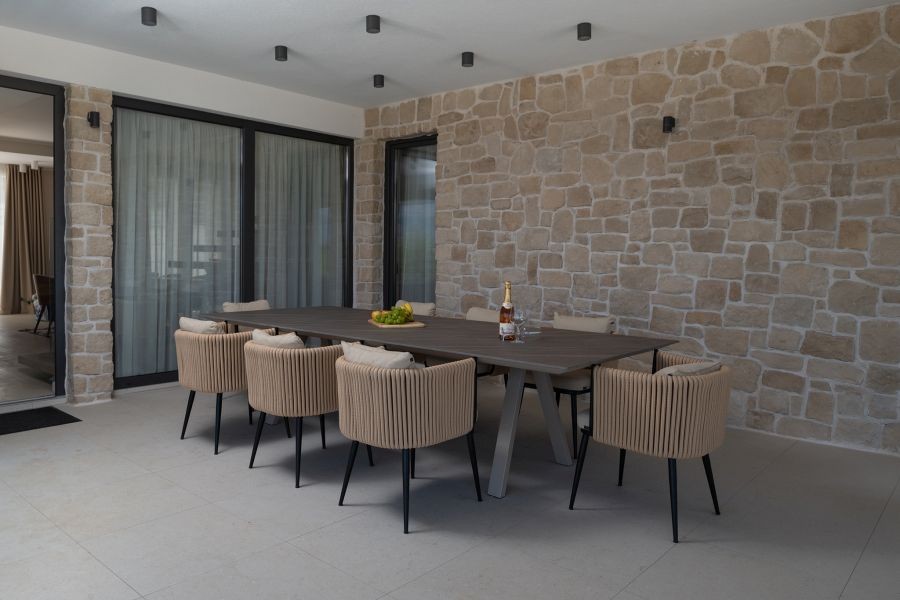 Überdachte Terrasse mit Esstisch und Natursteinwand