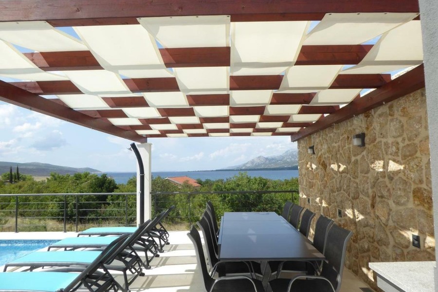 Überdachte Terrasse mit Esstisch und Meerblick