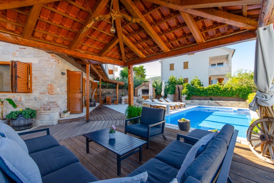 Überdachte Holzterrasse mit Sitzgruppe am Pool