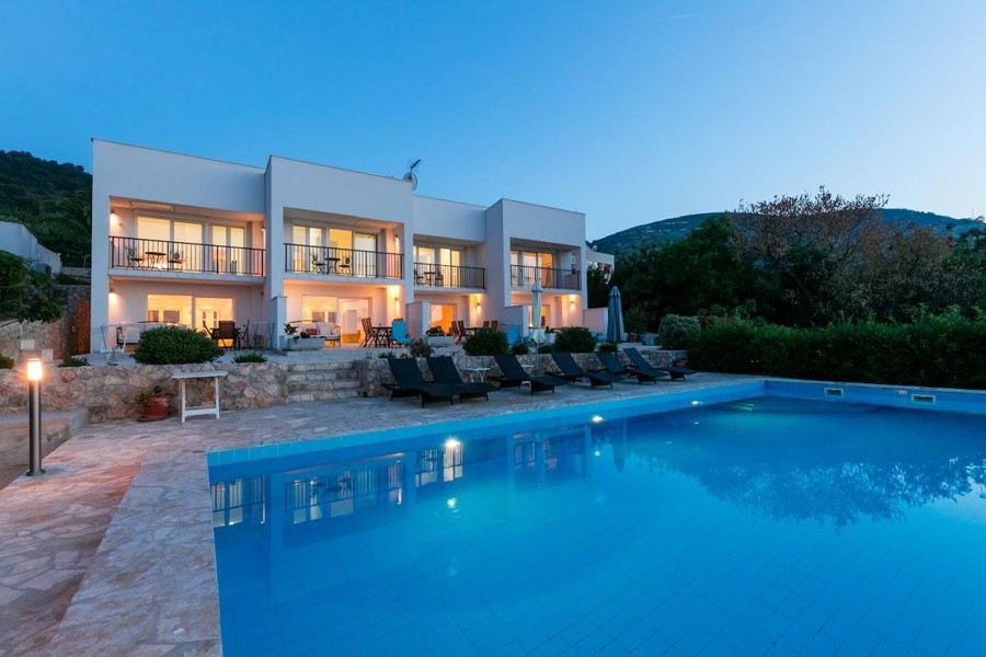 Apartmenthaus mit beleuchtetem Pool am Abend
