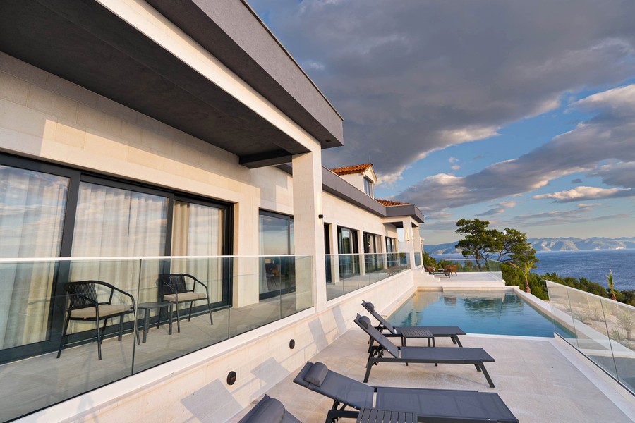 Terrasse mit Glasgeländer und Liegen am Pool
