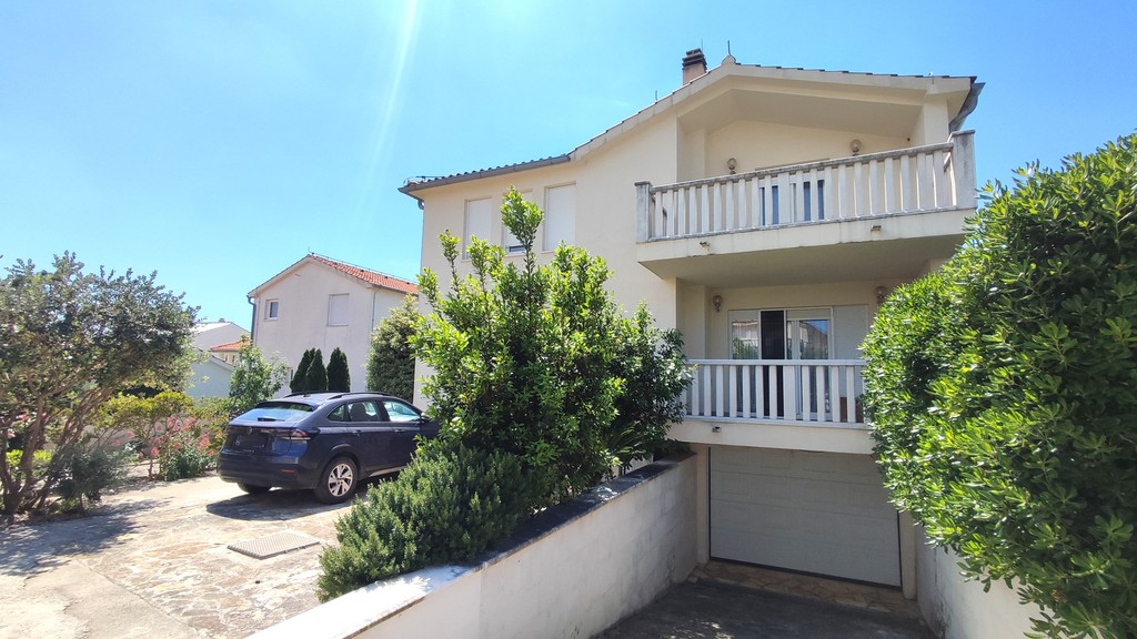 Hausfront mit Balkon und Garageneinfahrt