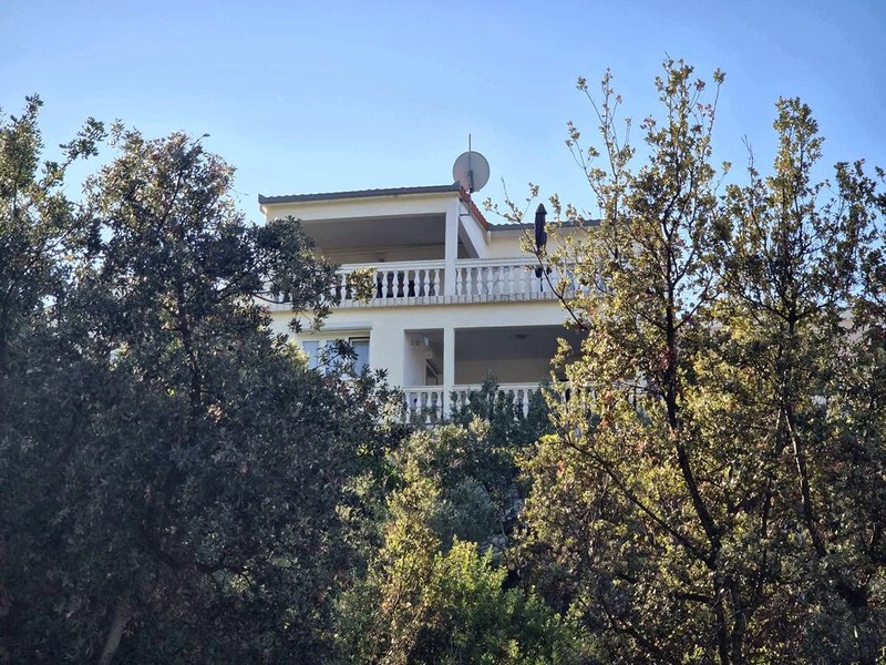 Hausansicht mit Balkon zwischen Olivenbäumen