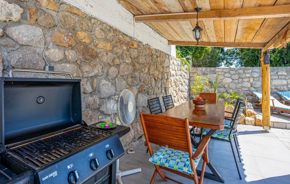 Überdachte Terrasse mit Grill und Esstisch