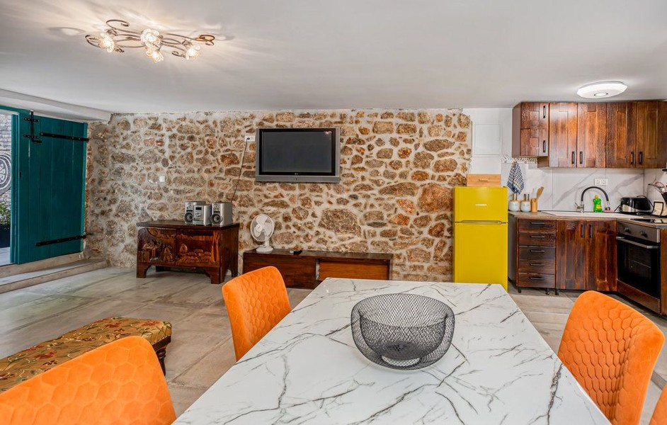 Esstisch vor Natursteinwand mit Fernseher