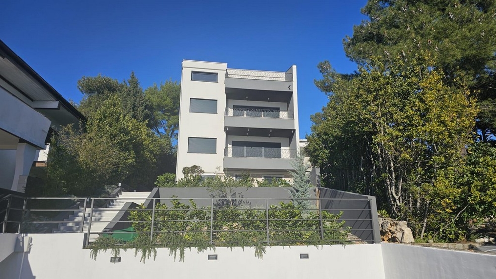 Außenansicht eines zeitgenössischen Apartmentgebäudes zum Verkauf in Crikvenica umgeben von üppigem Grün mit Meerblick