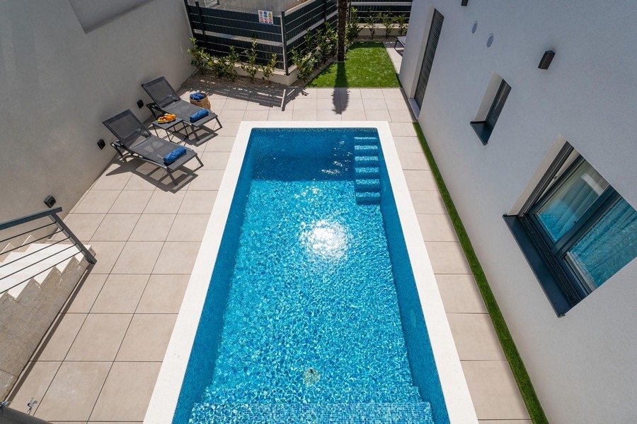 Pool mit Liegen von oben zwischen Hauswand und Zaun