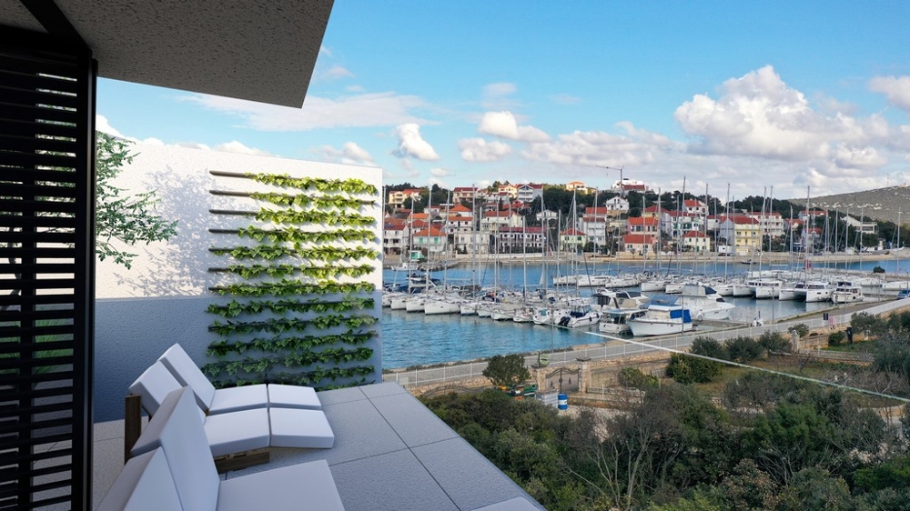 Aussicht von einer Immobilie in Kroatien auf einen Hafen mit Booten und traditionellen Gebäuden im Hintergrund.