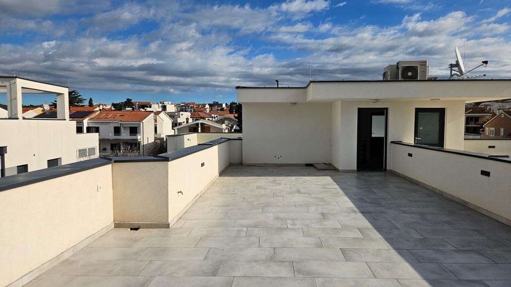 Große, private Dachterrasse eines zum Verkauf stehenden Penthouses in Zadar, Kroatien, umgeben von Gebäuden unter einem bedeckten Himmel
