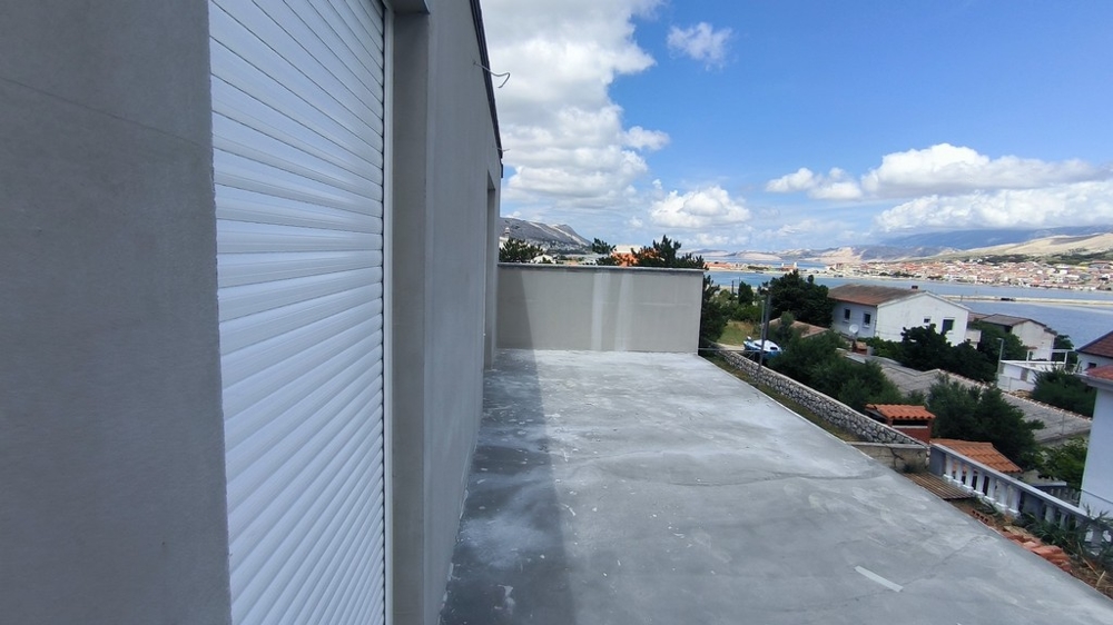 Überdachte Terrasse der Wohnung zum Verkauf in Pag, Kroatien, mit Ausblick auf ein geparktes Fahrzeug