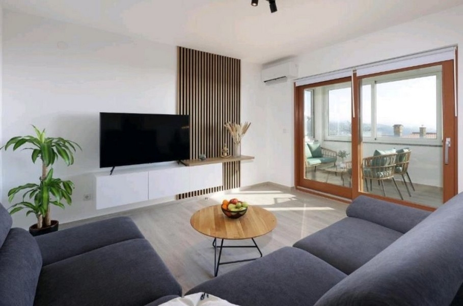 Wohnzimmer im modernen Apartment mit Couch, Tisch und Fernseher, Meerblick im Hintergrund, zum Verkauf bei Opatija, Kroatien