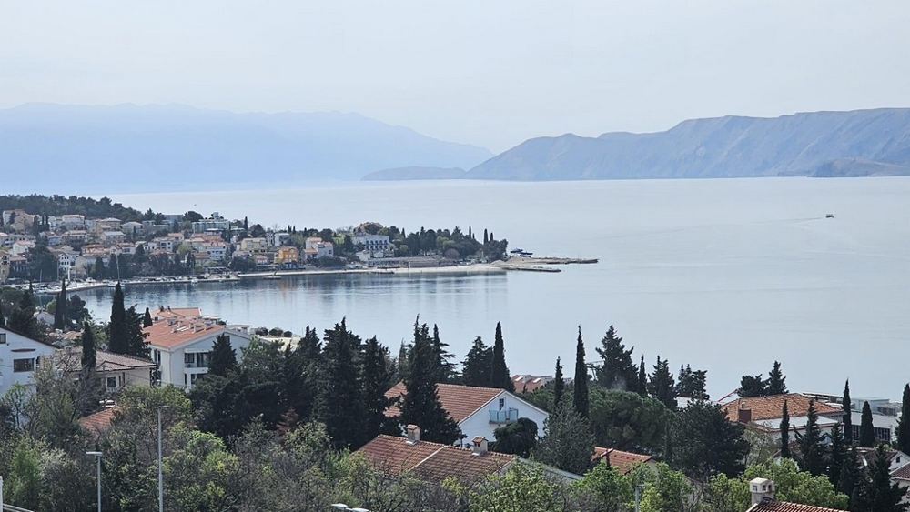 Aussicht auf eine Küstenstadt in Kroatien mit mehreren Gebäuden und einer klaren Sicht auf das Meer im Hintergrund. Immobilie Kroatien, Appartement mit Meerblick