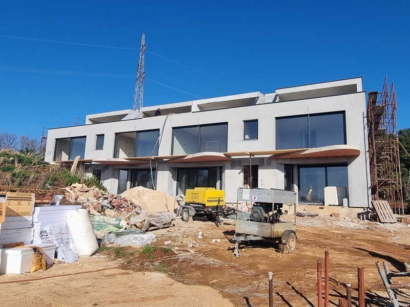 Moderne Reihenhäuser in Bau, Immobilien Kroatien, mit Baugeräten und Materialien im Vordergrund