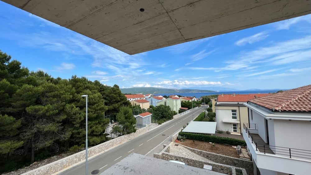 Aussicht von einem Balkon auf eine ruhige Straße zwischen Immobilien in Kroatien, mit Meer im Hintergrund