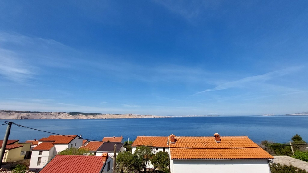 Immobilien Kroatien, Appartement mit Meerblick, Wohnung kaufen Kroatien, lick auf das Meer und die umliegenden Häuser mit roten Dächern unter einem klaren blauen Himmel.