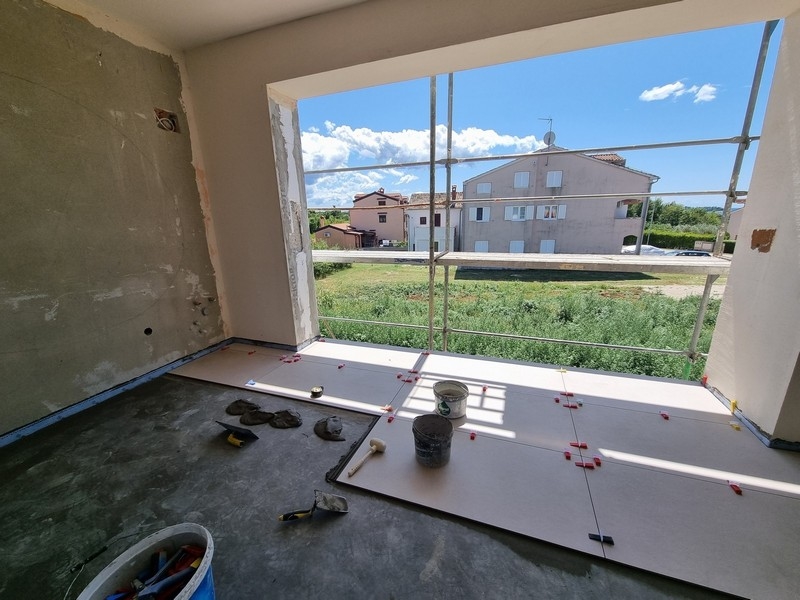 Blick aus einer unfertigen Wohnung, Baustelle, Fensteröffnung, Grünflächen