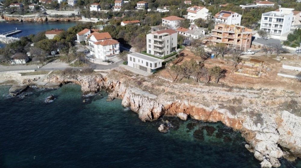 Luftaufnahme einer Küstenregion mit weißen Häusern, klarem Wasser und Felsen. Panorama Scouting, Wohnung kaufen Kroatien