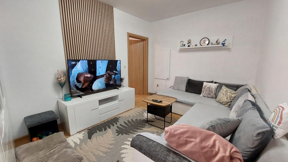 Helles Wohnzimmer mit großem Sofa und TV