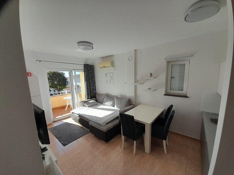Wohnbereich mit Sofa, Esstisch und Zugang zum Balkon mit Meerblick