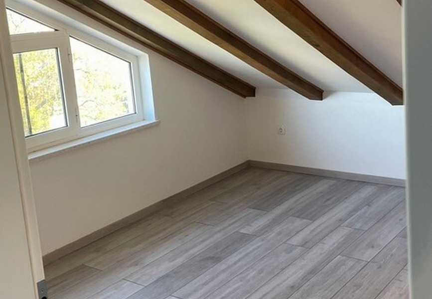 Zimmer im Dachgeschoss mit sichtbaren Dachbalken