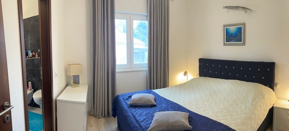 Schlafzimmer mit Doppelbett, Fenster und Zugang zum Bad