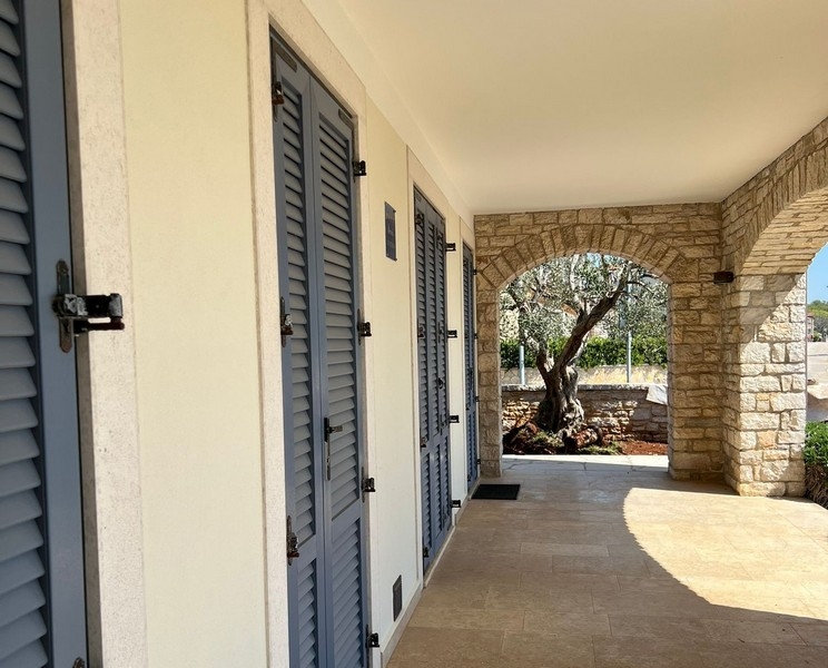 Überdachter Eingangsbereich mit Natursteinbögen und Fensterläden