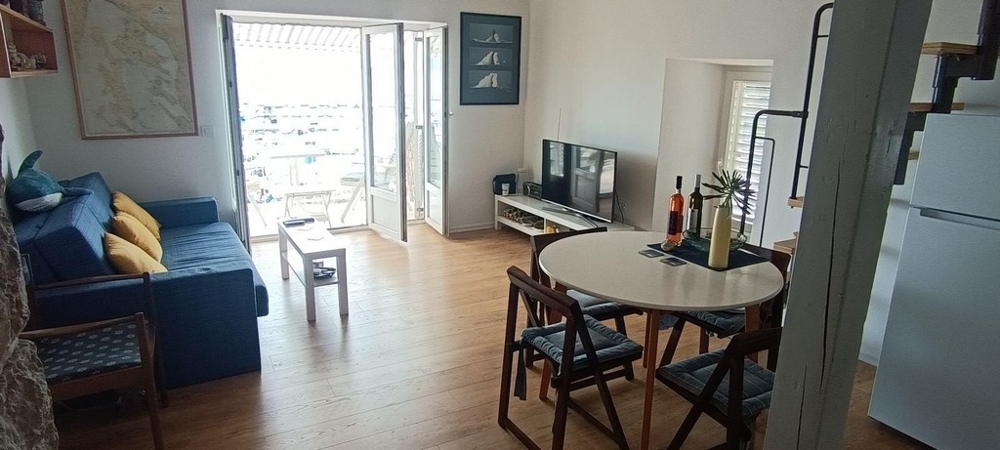 Wohnbereich mit Sofa, Esstisch und Balkonzugang mit Meerblick