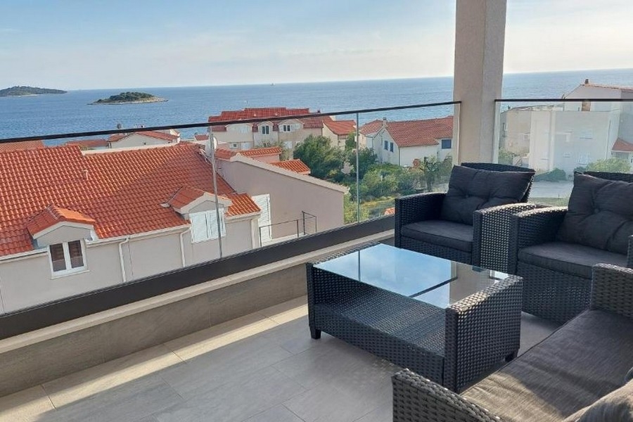 Balkon mit Sitzgruppe und Blick auf Küstenlinie und vorgelagerte Insel