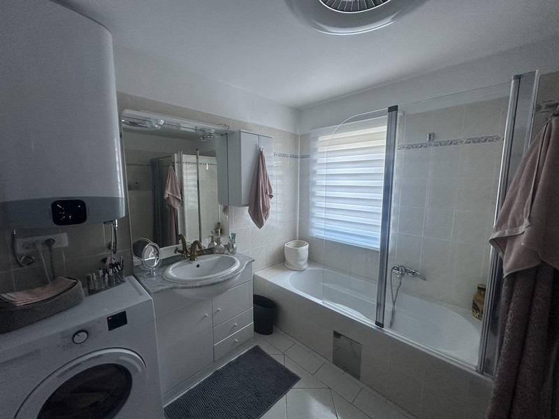 Badezimmer mit Badewanne, Waschbecken und Waschmaschine