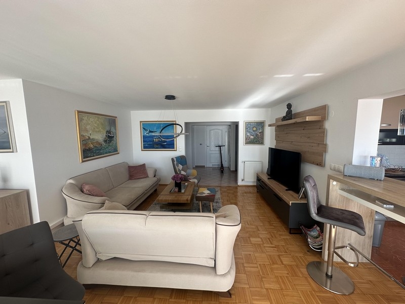 Wohnzimmer mit Sofalandschaft und offenem Übergang zur Küche