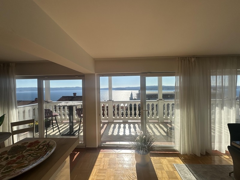 Wohnbereich mit großer Fensterfront und Zugang zum Balkon mit Meerblick