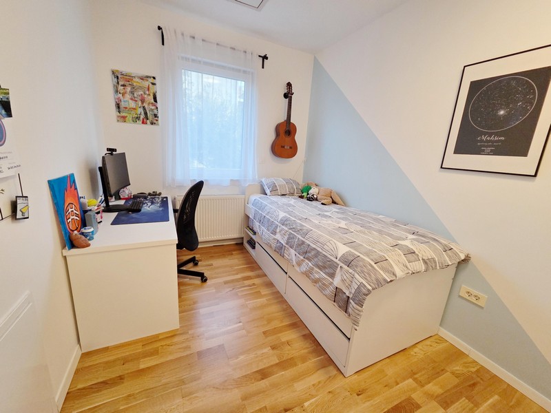 Jugendzimmer mit Schreibtisch, Bett und Gitarre an der Wand