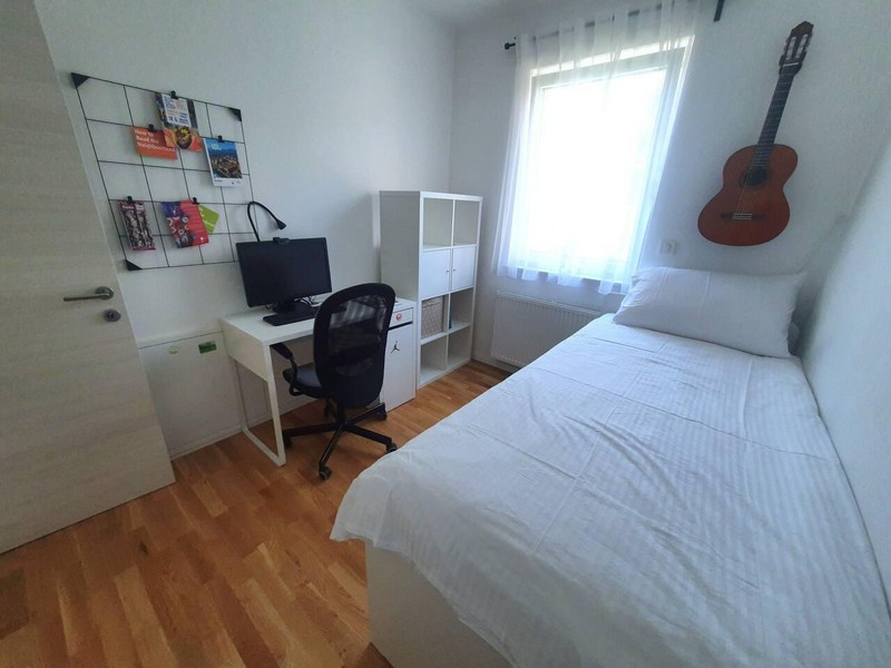 Zimmer mit Einzelbett, Schreibtisch und Regal