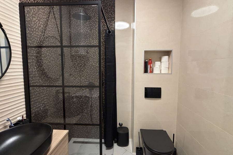 Badezimmer mit Dusche und schwarzen Armaturen