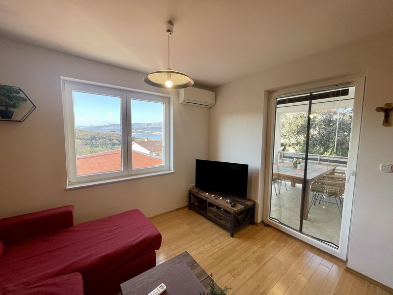 Wohnzimmer mit Sofa, TV und Balkonzugang mit Blick auf das Meer