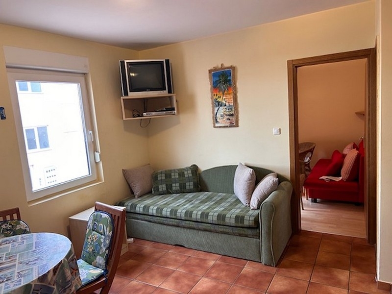 Kompakter Wohnraum mit Sofa, Fernseher und Zugang zum Schlafzimmer