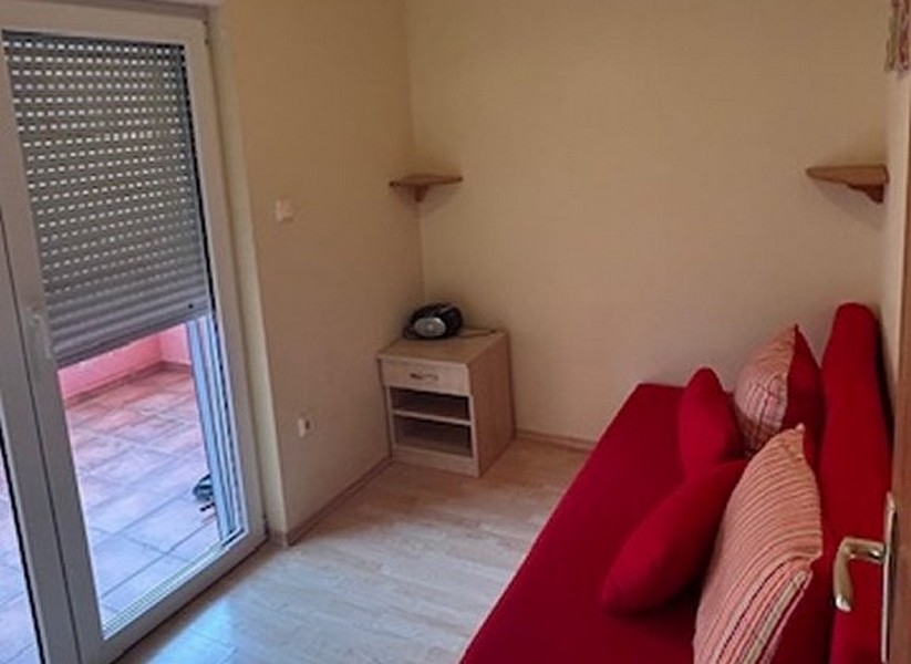 Schlafzimmer mit rotem Sofa und Zugang zum Balkon